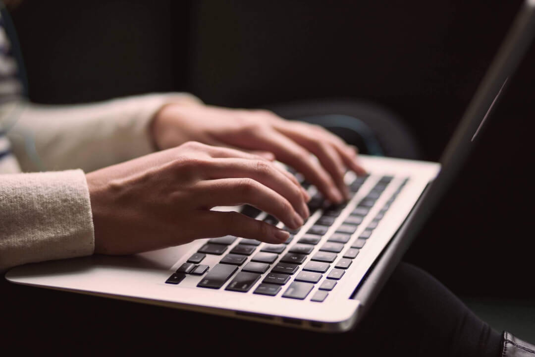 Payroll administrator typing on laptop